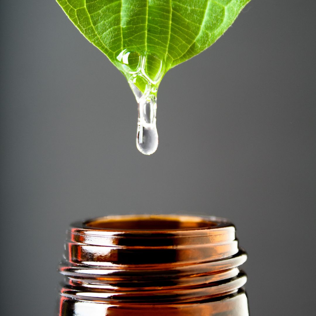 Close-up of a green leaf dripping a clear drop into an open amber glass bottle