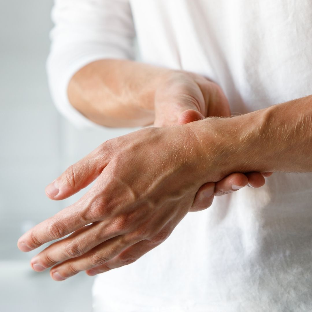 Close-up of a person holding their wrist in pain, indicating carpal tunnel or nerve pain