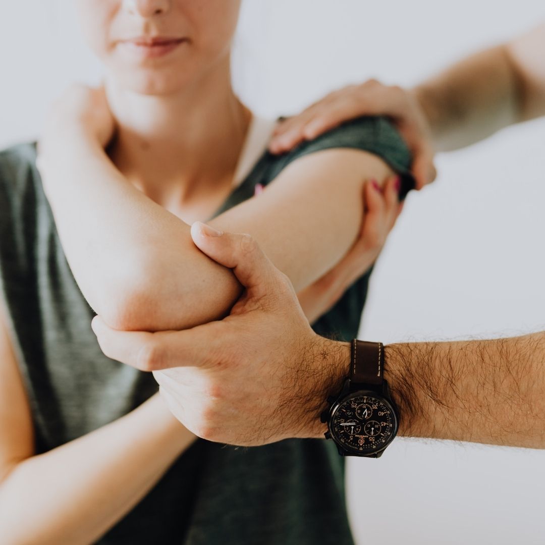 Therapist assisting a patient with an elbow stretch to improve joint mobility in a bright clinical setting