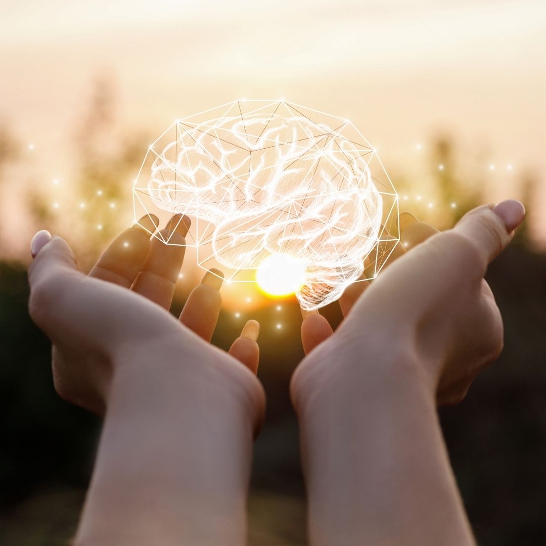 Hands cupping a glowing holographic brain above a sunset, representing memory and brain health