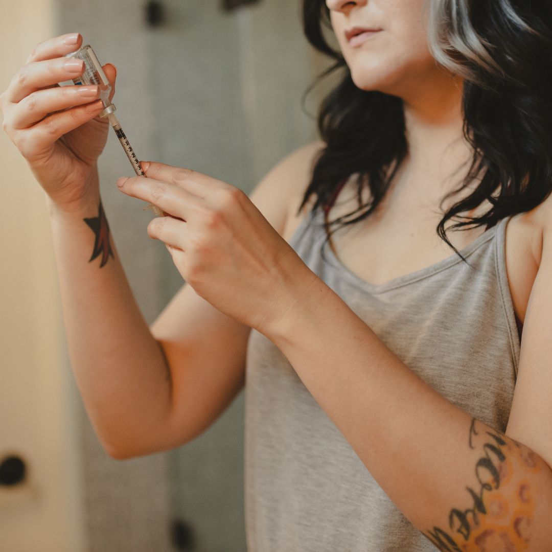 Woman preparing a syringe from a medication vial in a bathroom