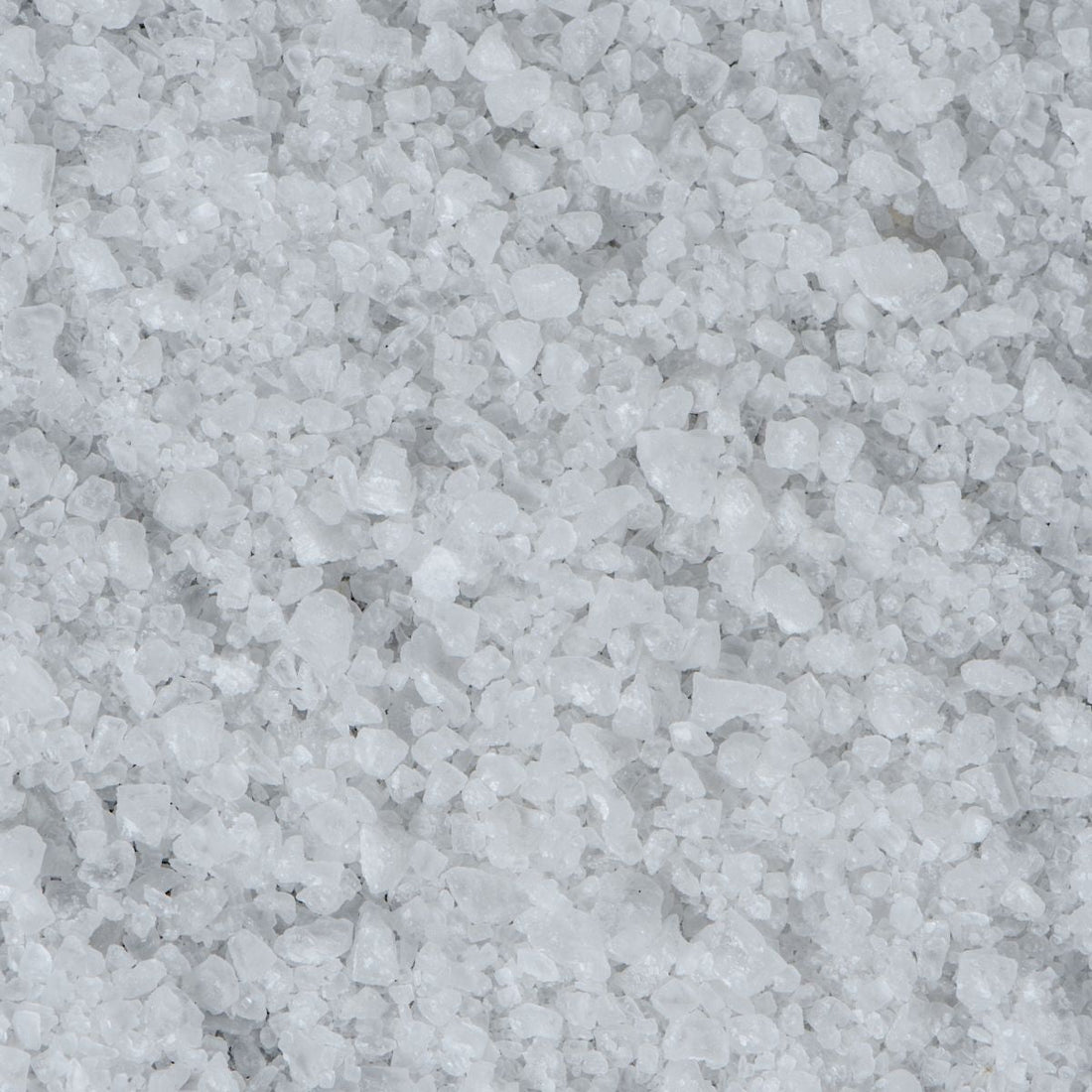 Close-up of Natrum muriaticum (sodium chloride) crystals showcasing coarse white salt granules covering the frame