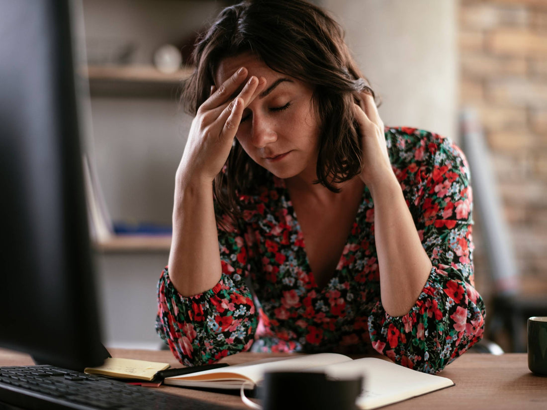 Woman pressing her temple with eyes closed, appearing to have a migraine