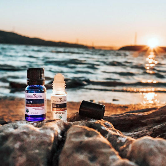 Forces of Nature Medicine Wart treatment vials on a sandy beach during sunset.
