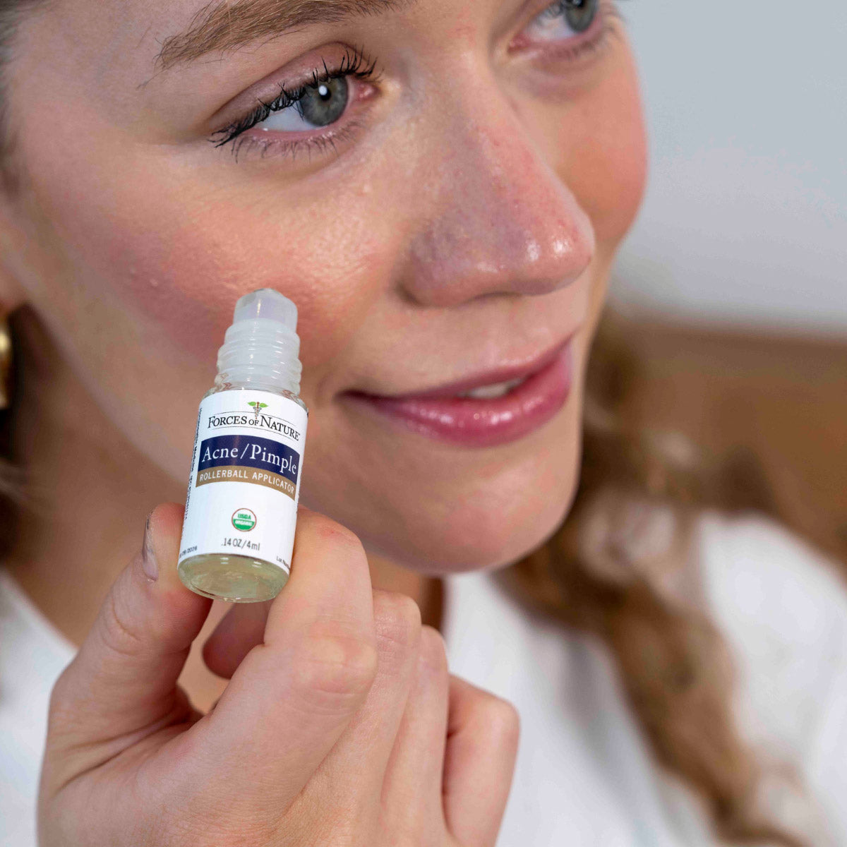 Woman applying Forces of Nature Acne Pimple Rollerball Applicator to face.