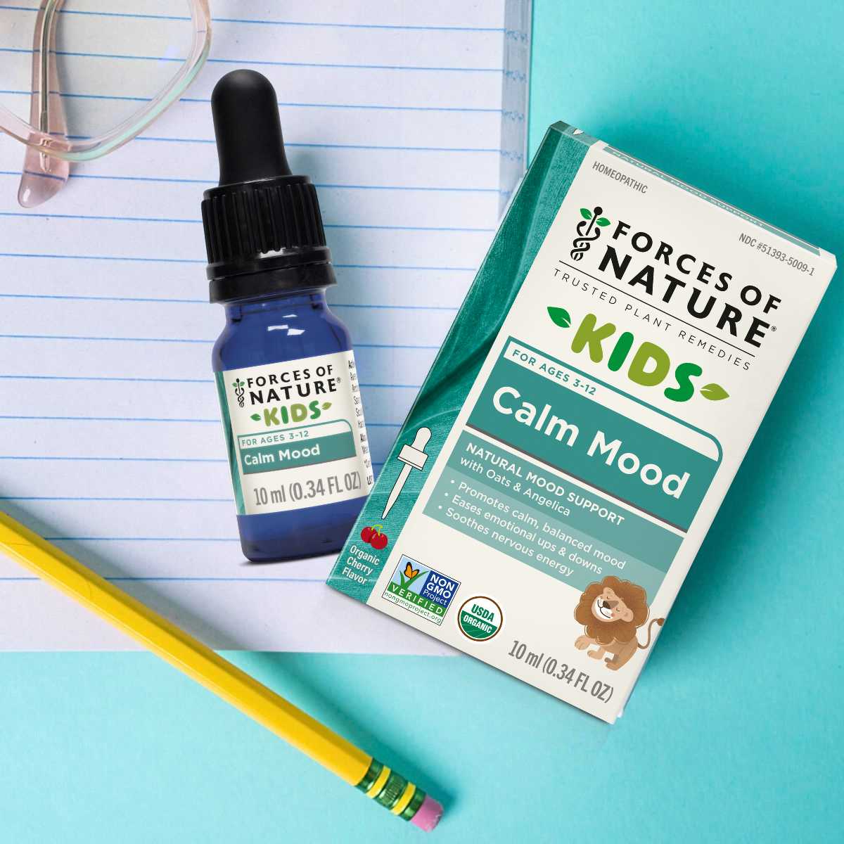 Bottle and packaging of Forces of Nature Kids Calm Mood supplement on a notebook and pencil with a blue background